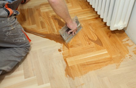 Varnishing of oak parquet floor, workers hand and tool